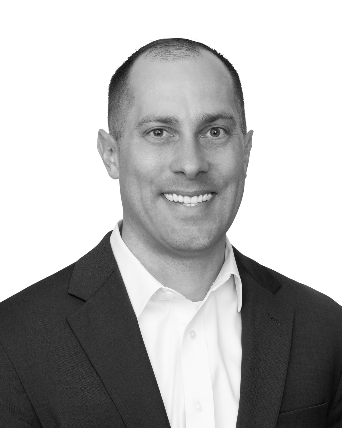 Black-and-white portrait: dark suit, open collar, direct to camera